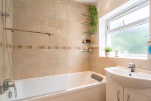 a bathroom with a tub and a sink and a window at K Suites - Liverpool Road Worcester with Hot Tub in Worcester