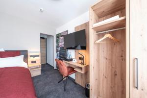 a bedroom with a bed and a desk with a television at Krone 1516 in Elchingen