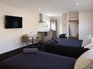 a room with two beds and a kitchen with a table at Taupo Debretts Spa Resort in Taupo