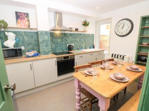 a kitchen with a table and a clock on the wall at 8 Manor Villas in Totland +27 photos