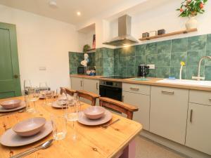 a kitchen with a wooden table with plates and glasses on it at 8 Manor Villas in Totland