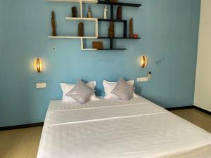 a blue bedroom with a large white bed with pillows at Sea Tide by Jade Rock in Negombo