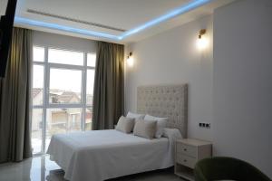 a bedroom with a white bed and a large window at HOTEL DON RAMIRO in Montilla