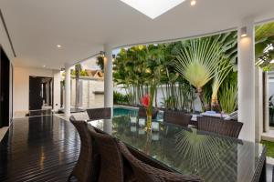 an indoor dining room with a glass table and chairs at Villa Maharani in Seminyak