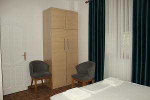 a bedroom with two chairs and a cabinet and a bed at Vila Sosana in Qeparo