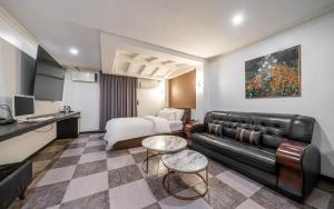 a living room with a black leather couch and a bed at Hotel The Fine in Uijeongbu