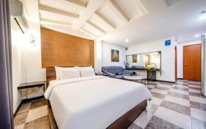 a bedroom with a large white bed and a living room at Hotel The Fine in Uijeongbu