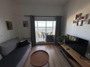 a living room with a couch and a television and a balcony at Appartement face mer Le Croisic , piscine privée et plage in Le Croisic