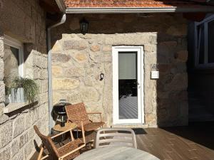 a patio with chairs and a door to a stone building at Chalet Villas Gerês in Geres