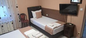 a small bedroom with a bed and a television at Къща за гости "Чекичев" in Svilengrad