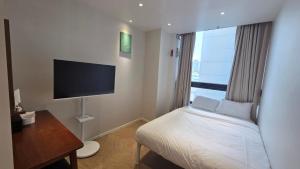a hotel room with a bed and a flat screen tv at Mumum Jongno in Seoul