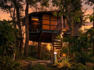 a tree house in the forest at sunset at Pugmarks Jungle Resort in Chegāt