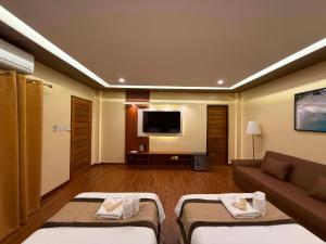 a hotel room with two beds and a couch at Balai Amihan Bed & Breakfast in Talisay