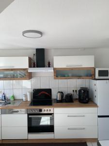a kitchen with white cabinets and a stove top oven at Ferienwohnung Geiseltalsee Frankleben in Frankleben