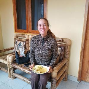 a woman sitting on a bench holding a plate of food at Tetebatu Clove Garden in Tetebatu +67 photos