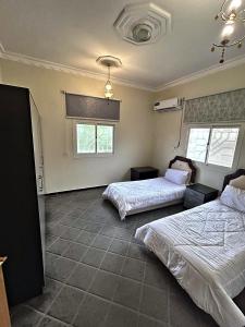a bedroom with two beds and two windows at شقة مدخل خاص بمدخلين in Tanomah