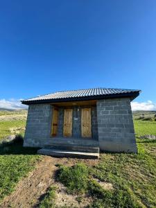 a small house with wooden doors in a field at Sky yurt camp in Këk-Say