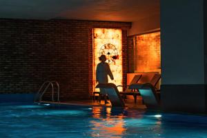 a person standing next to a swimming pool at night at GRANO HOTEL Gdańsk Riverside in Gdańsk