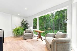 a living room with two chairs and a table and a large window at Spa & River - Le Saint-Gabriel in Saint-Gabriel-De-Valcartier