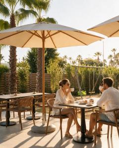 a man and woman sitting at a table under an umbrella at Azel Boutique Hotel in Draç