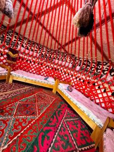 a bed with colorful rugs on the floor at Sky yurt camp in Këk-Say +2 photos