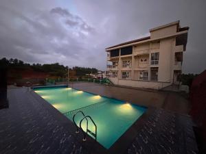 a large swimming pool in front of a building at Sansav Garden Resort in Gurpur
