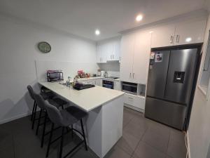 a kitchen with white cabinets and a black refrigerator at Private Room with Queen Bed & Bathroom in Bellbird Park