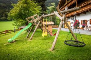a wooden playground with swings and a slide at Vorderkasbichlhof in Saalfelden am Steinernen Meer