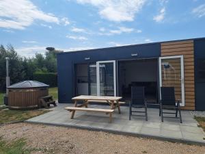 a blue house with a picnic table and two chairs at Cube 97 I 4 persoons chalet met hottub in Zennewijnen +28 photos