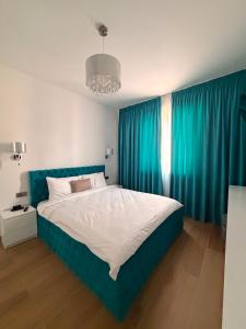 a bedroom with a large bed with blue curtains at Adinna Residence in Giroc