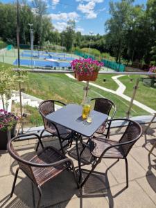 a table with chairs and a vase with flowers on it at Hotel FairPlayce in Poznań