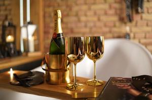 a bottle of champagne and two wine glasses on a table at Magik Love Apartament in Piła +49 photos