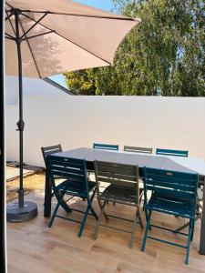 a table with four chairs and an umbrella at Villa Métisse Ile et Villas Groix in Groix