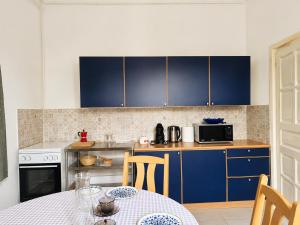 a kitchen with blue cabinets and a table with chairs at Dinnyés Kúria Dabas in Dabas