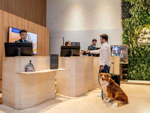 a man with a dog sitting at a cash register at Grand Mercure SP Itaim Bibi in São Paulo