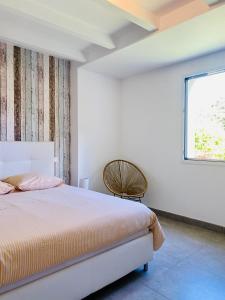 a white bedroom with a bed and a window at Villa Métisse Ile et Villas Groix in Groix