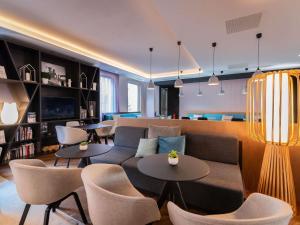 a living room with a couch and tables and chairs at Novotel Suites Colmar Centre in Colmar