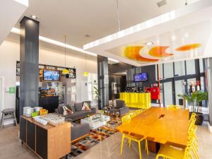 a living room with a wooden table and yellow chairs at ibis Styles Boa Vista in Boa Vista