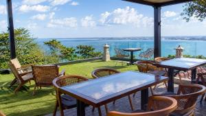 a patio with tables and chairs and a view of the water at Del Cielo Villa Jimbaran in Jimbaran
