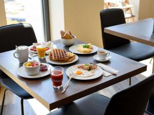 a table with breakfast foods and drinks on it at Aparthotel Adagio Bremen City in Bremen
