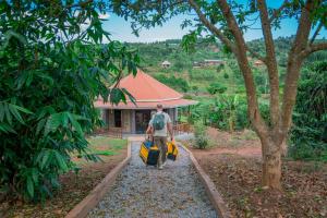 a man walking down a path with luggage in front of a house at Gejja Cottage in Lwanga
