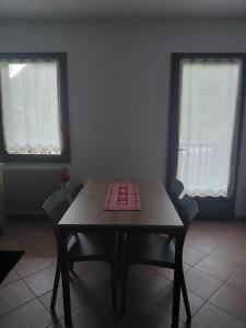 a table and chairs in a room with two windows at Dolce casa in Saone