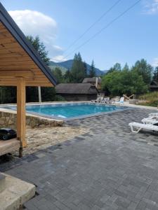a swimming pool with chairs and a pavilion at Горянка in Guta