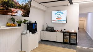 a kitchen with white cabinets and a tv on a wall at Paradise Pods in Gold Coast