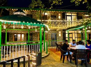 people sitting at a table in front of a building with lights at The Woods Boho in Nainital