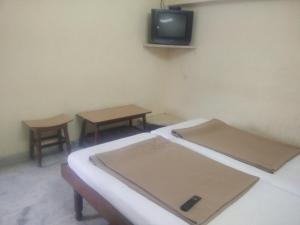 a room with two beds and a tv on the wall at MSR Lodge in Tirupati