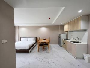 a bedroom with a bed and a table and a kitchen at Suntomoon Residence By Sumo Ayutthaya อยุธยา in Phra Nakhon Si Ayutthaya