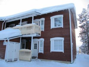 ein rotes Backsteinhaus mit Balkon im Schnee in der Unterkunft Lapin Kutsu Holiday Homes in Saariselkä