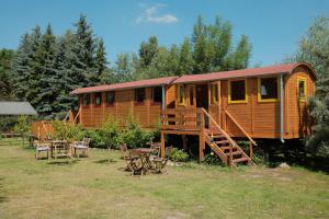 a wooden cabin with tables and chairs in front of it at Sonnenhof Uckermark in Lübbenow