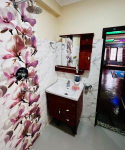 a bathroom with a sink and a flower wallpaper at Sumitra Niwas-Home Away from Home in Bālāju +2 photos